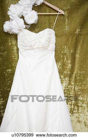 Stock Photo - Rose flowers and wedding dress on clothes hanger. Fotosearch