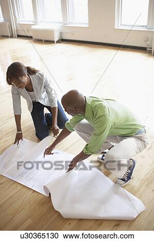 Architects looking at blueprints in empty room (high angle view) View Large Photo Image Stock Image - Architects looking at blueprints in empty room (high angle view). Fotosearch