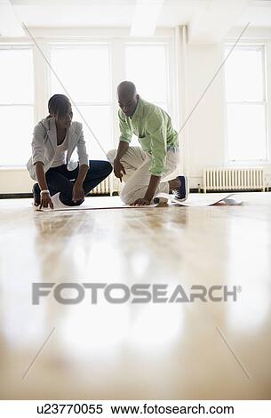 Architects looking at blueprints in empty room View Large Photo Image Stock Photography - Architects looking at blueprints in empty room. Fotosearch