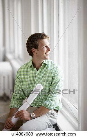 Stock Image - Man sitting and looking through window. Fotosearch