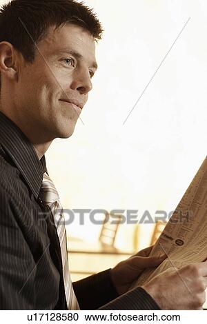 Stock Image - Mid adult man reading newspaper. Fotosearch