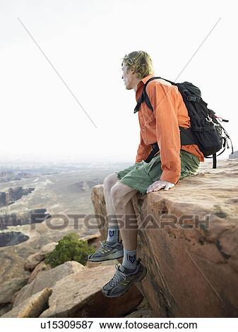 Male hiker sitting on cliff View Large Photo Image Stock Photo - Male hiker sitting on cliff. Fotosearch