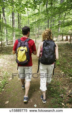 Stock Photography - Man and woman hiking in forest (rear view). Fotosearch
