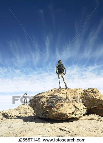 Stock Photo - Man and woman standing on boulders. Fotosearch