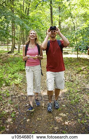 Stock Image - Man and woman watching birds in forest. Fotosearch