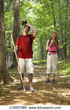 Stock Photo - Man and woman watching birds in forest. Fotosearch