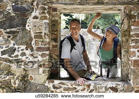 Stock Photography - Mid adult couple looking through window of ruined building. Fotosearch