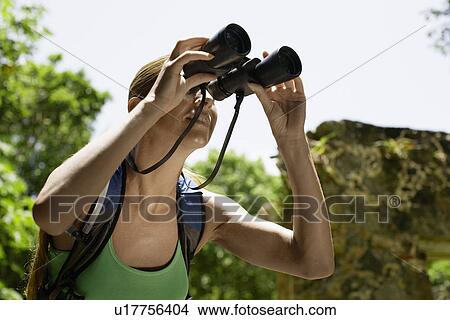 Picture - Mid adult woman looking through binoculars. Fotosearch