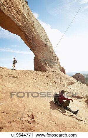 Two men hiking on red rocks, Moab, Utah, USA View Large Photo Image Stock Image - Two men hiking on red rocks, Moab, Utah, USA. Fotosearch