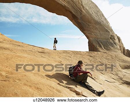 Stock Photograph - Two men hiking on red rocks, Moab, Utah, USA. Fotosearch