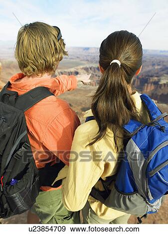 Stock Photo - Young couple looking at rock strata, rear view. Fotosearch
