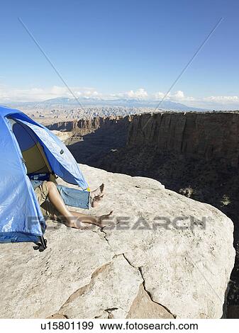 Stock Photo - Couple sleeping in tent by cliff, high angle view, Moab, Utah, USA. Fotosearch