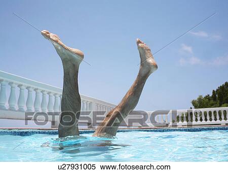 Stock Photography - Man doing handstand in swimming pool, legs above surface. Fotosearch