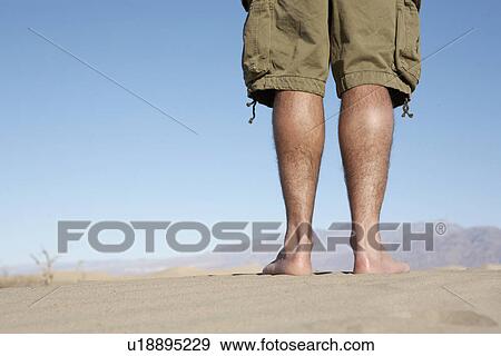Man standing on sand (low section) View Large Photo Image Stock Photo - Man standing on sand (low section). Fotosearch