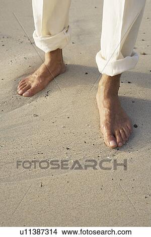 Picture - Man's bare feet on sand (focus on feet). Fotosearch