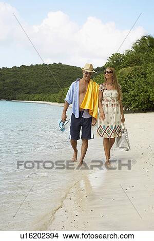 Mid adult couple walking on sandy beach, St. John, US Virgin Islands, USA View Large Photo Image Picture - Mid adult couple walking on sandy beach, St. John, US Virgin Islands, USA. Fotosearch