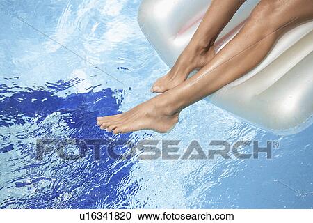 Stock Image - Woman's legs on pool raft. Fotosearch