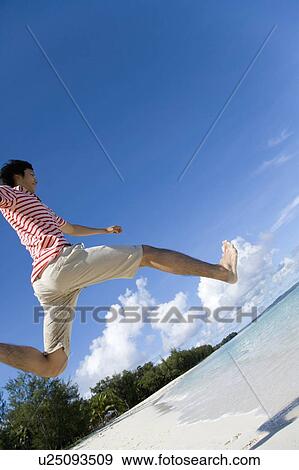 Stock Photo - Man jumping on beach, Saipan, USA . Fotosearch