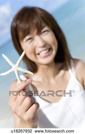 Portrait of a young woman holding a starfish, smiling, differential focus, Saipan, USA View Large Photo Image Stock Image - Portrait of a young woman holding a starfish, smiling, differential focus, Saipan, USA . Fotosearch
