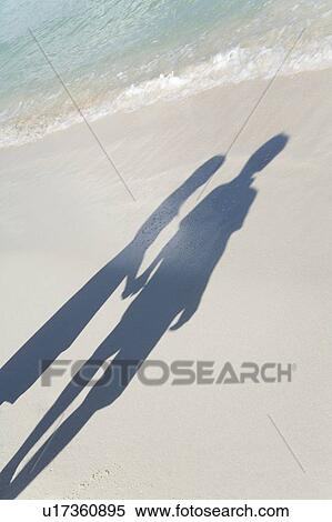 Stock Photography - Shadow of young couple on beach, hand in hand, Saipan, USA . Fotosearch
