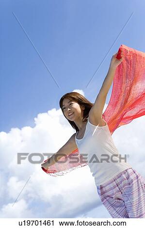 Stock Image - Woman holding fabric behind back on beach, smiling, Saipan, USA . Fotosearch
