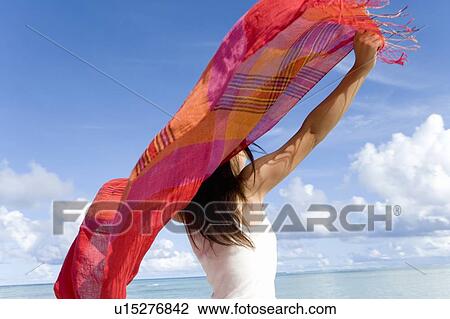 Stock Image - Woman holding fabric behind her back on beach, Saipan, USA . Fotosearch