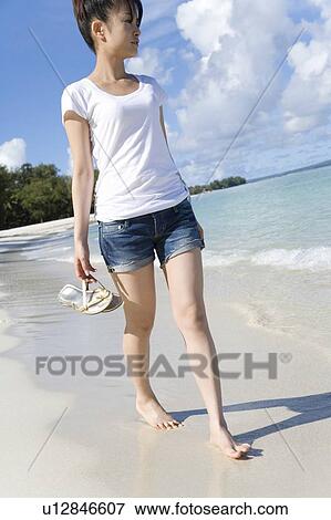 Woman walking on beach, holding sandals, Saipan, USA View Large Photo Image Stock Photo - Woman walking on beach, holding sandals, Saipan, USA . Fotosearch