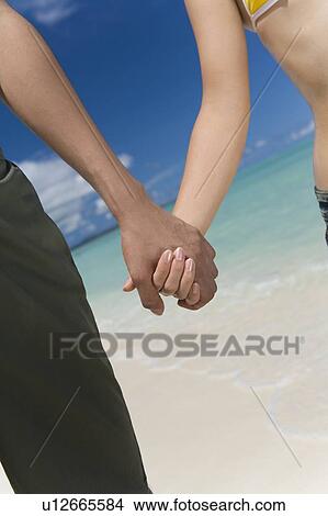 Picture - Young couple on beach, hand in hand, Saipan, USA . Fotosearch