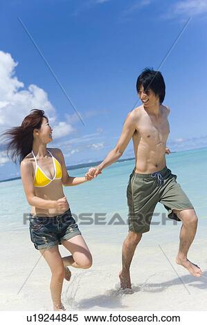 Stock Photography - Young couple running on beach, smiling, Saipan, USA . Fotosearch
