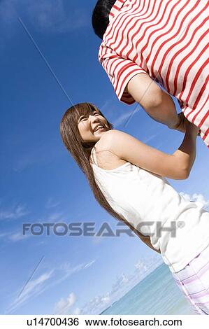 Stock Photograph - Young couple standing on beach, woman looking back, Saipan, USA . Fotosearch