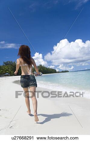 Young woman running on beach, holding sandals, Saipan, USA View Large Photo Image Stock Image - Young woman running on beach, holding sandals, Saipan, USA . Fotosearch