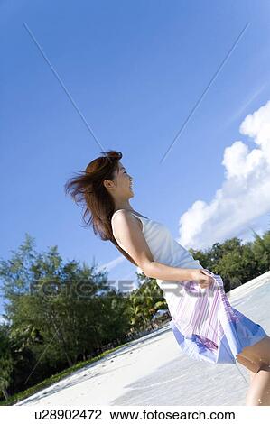 Stock Image - Young woman walking on beach, smiling, Saipan, USA . Fotosearch