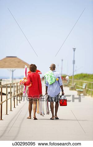 Man and woman carrying picnic equipment at beach (rear view), Spring Lake, New Jersey, USA View Large Photo Image Stock Photography - Man and woman carrying picnic equipment at beach (rear view), Spring Lake, New Jersey, USA. Fotosearch