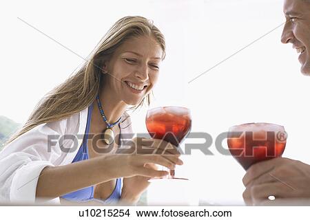 Picture - Mid adult couple in beach attire having cocktails. Fotosearch