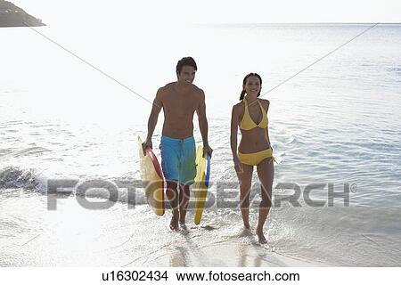 Picture - Young couple with bodyboards walking in ocean, St. John, US Virgin Islands, USA. Fotosearch