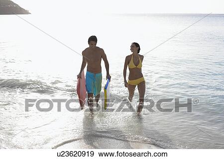 Young couple with bodyboards walking in ocean, St. John, US Virgin Islands, USA View Large Photo Image Stock Photo - Young couple with bodyboards walking in ocean, St. John, US Virgin Islands, USA. Fotosearch