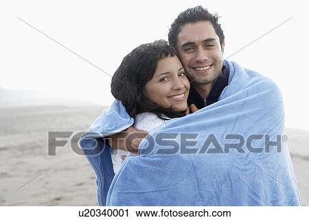 Stock Image - Young couple wrapped in towel (portrait). Fotosearch