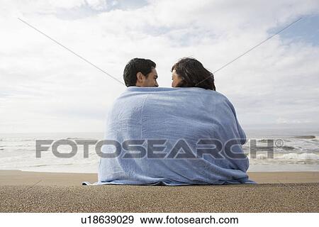 Jeune Couple Emballé Dans Serviette Sur Plage Rear View Banque De Photo