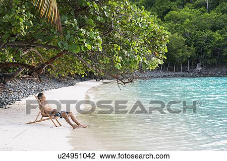 Mid adult man sitting on lounge chair on sandy beach, St. John, US Virgin Islands, USA View Large Photo Image Stock Image - Mid adult man sitting on lounge chair on sandy beach, St. John, US Virgin Islands, USA. Fotosearch