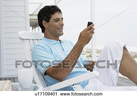 Mid adult man text messaging near beach View Large Photo Image Stock Image - Mid adult man text messaging near beach. Fotosearch