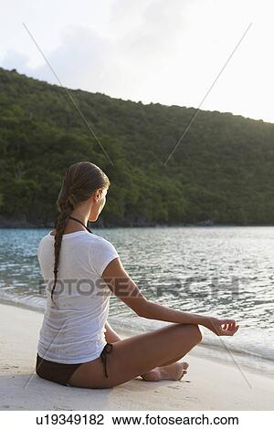 Mid adult woman meditating in lotus position on sandy beach, St. John, US Virgin Islands, USA View Large Photo Image Stock Image - Mid adult woman meditating in lotus position on sandy beach, St. John, US Virgin Islands, USA. Fotosearch