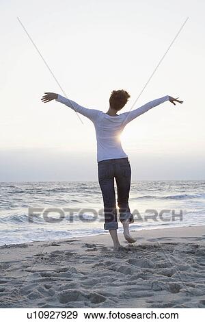 Mid adult woman running on beach (rear view) View Large Photo Image Stock Photo - Mid adult woman running on beach (rear view). Fotosearch
