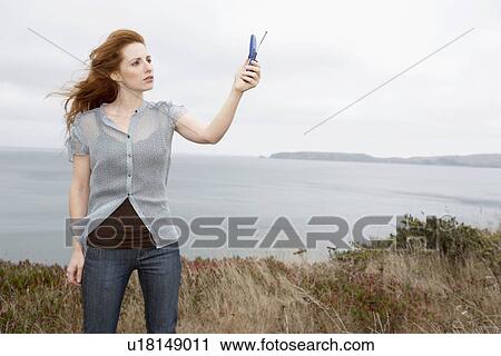 Woman holding cell phone at beach View Large Photo Image Stock Image - Woman holding cell phone at beach. Fotosearch