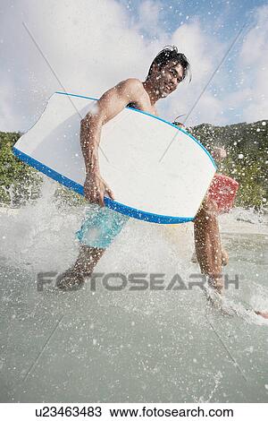 Young man with bodyboard walking in water View Large Photo Image Stock Image - Young man with bodyboard walking in water. Fotosearch