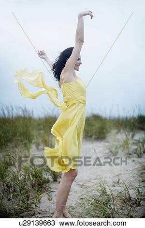 Stock Image - Young woman raising hands on beach. Fotosearch