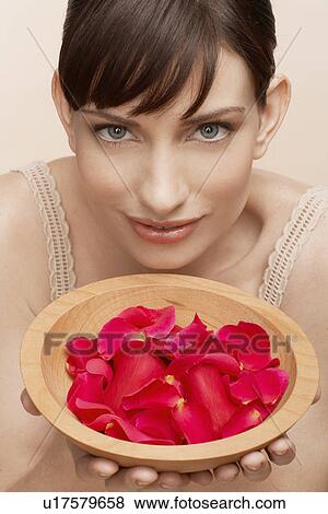 Stock Photo - Mid adult woman holding bowl of petals. Fotosearch