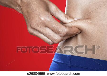 Stock Photography - Woman Pinching Skin Around Abdominals. Fotosearch
