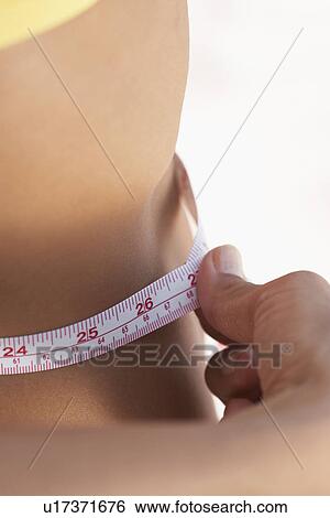 Young woman measuring tape (midsection) View Large Photo Image Stock Photograph - Young woman measuring tape (midsection). Fotosearch