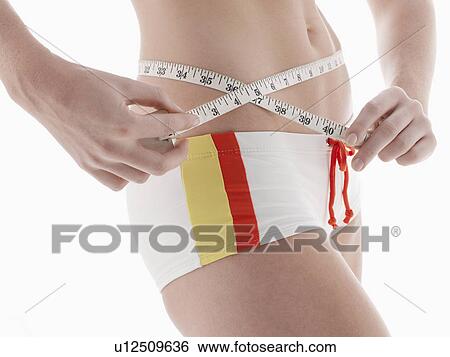 Young woman measuring waist (close-up) View Large Photo Image Stock Photograph - Young woman measuring waist (close-up). Fotosearch
