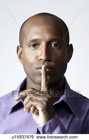 Mid adult man holding index finger on lips View Large Photo Image Stock Photo - Mid adult man holding index finger on lips. Fotosearch